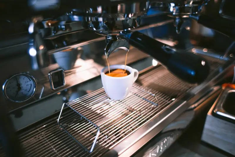Espresso läuft aus dem Siebträger in eine weiße Tasse