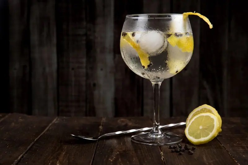 Gin Tonic mit Zitrone auf dunklem Holz