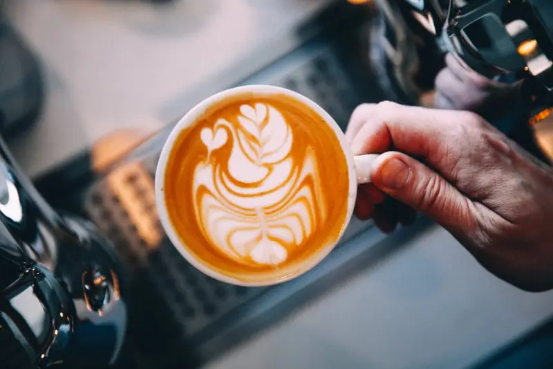 Cappuccino mit Latte Art in der Hand